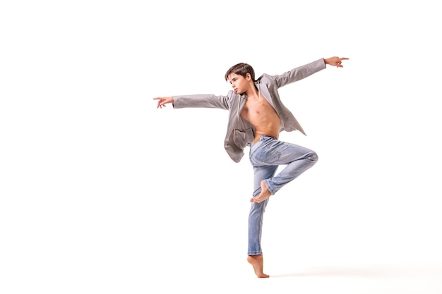 Un danseur de ballet adolescent pose pieds nus, isolé sur fond blanc.