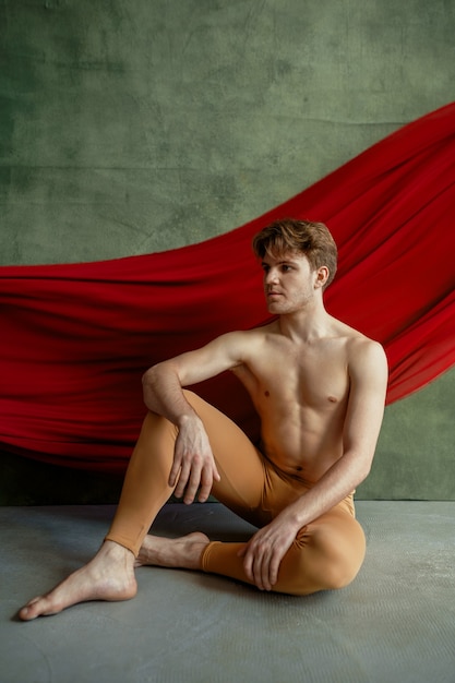 Danseur de ballet masculin, studio de danse, mur de grunge et tissu rouge sur fond