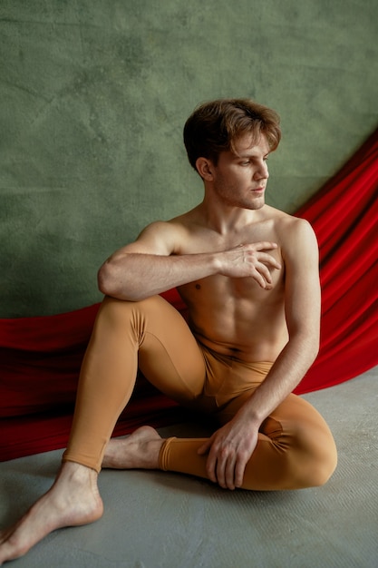 Danseur de ballet masculin, studio de danse, mur de grunge et tissu rouge. Interprète au corps musclé, grâce et élégance des mouvements