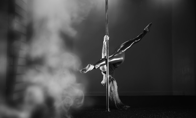 Le danseur sur le pylône en studio. Fille faisant des exercices sur un équipement sportif.