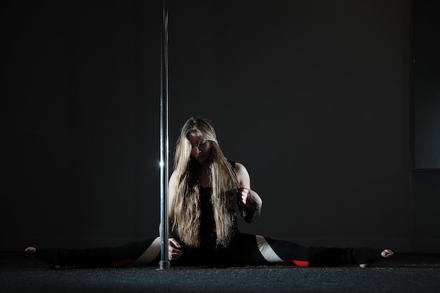 Le danseur sur le pylône en studio. Fille faisant des exercices sur un équipement sportif.