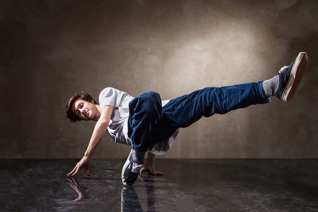 Danseur urbain de hip hop avec texture de fond de mur de béton grunge sautant et dansant