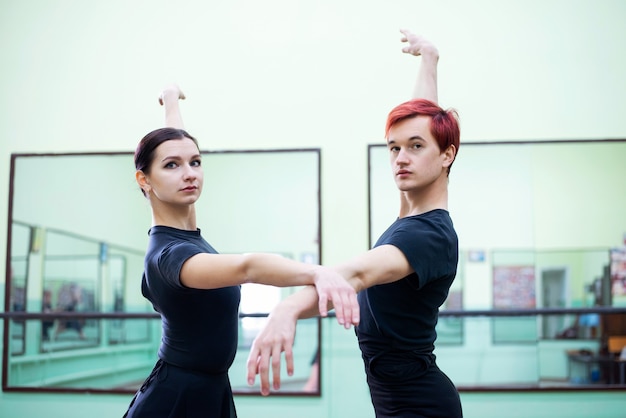 Danseurs de ballet élégants et gracieux dans une salle lumineuse pratiquant leur danse