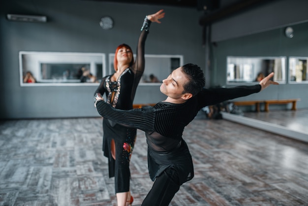 Danseurs d'élégance en costumes sur la formation de danse ballrom en classe.