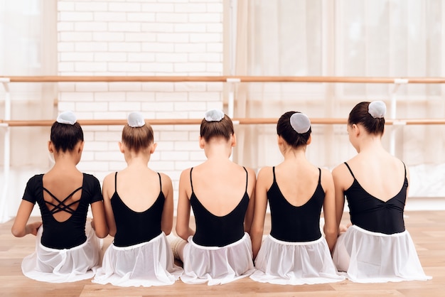 Danseurs enfants assis dans la rangée avec dos à la caméra.