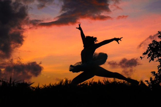 Photo une danseuse de ballet en silhouette sautant tout en dansant contre le ciel au coucher du soleil