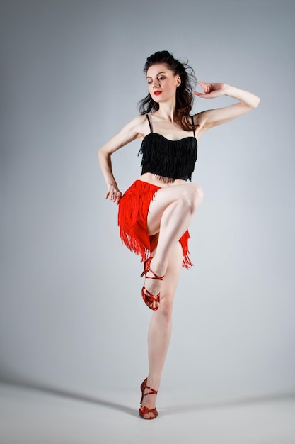 Une danseuse élégante exécute une danse latino-américaine dans une élégante robe rouge avec des bijoux étincelants Mode et beauté Spectacle de ballet Portrait en studio