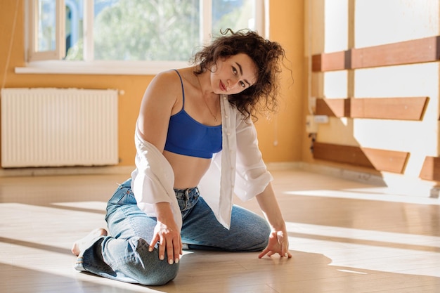 Danseuse jeune fille en vêtements décontractés dansant la danse contemporaine à l'intérieur de la salle dans les lumières du soleil du matin