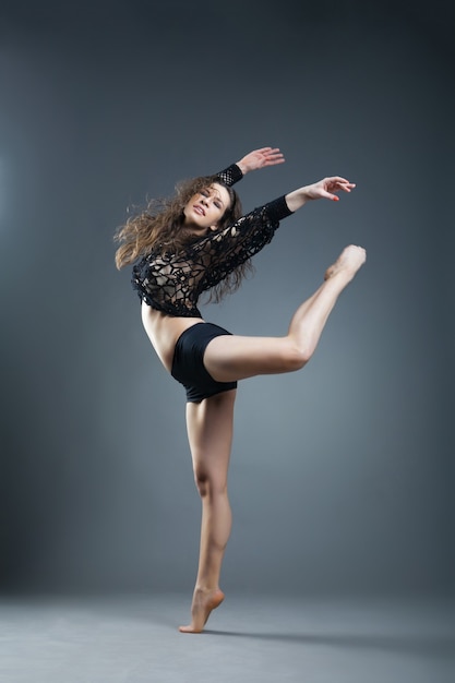 Danseuse de style moderne posant sur un fond gris studio