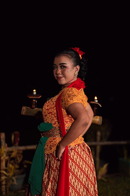 Une danseuse traditionnelle asiatique vêtue d'une robe orange avec un foulard rouge et un maquillage se produisant au festival de danse