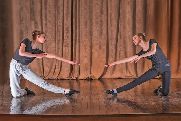 Les danseuses de jeunes filles travaillent sur des mouvements de danse sur scène.