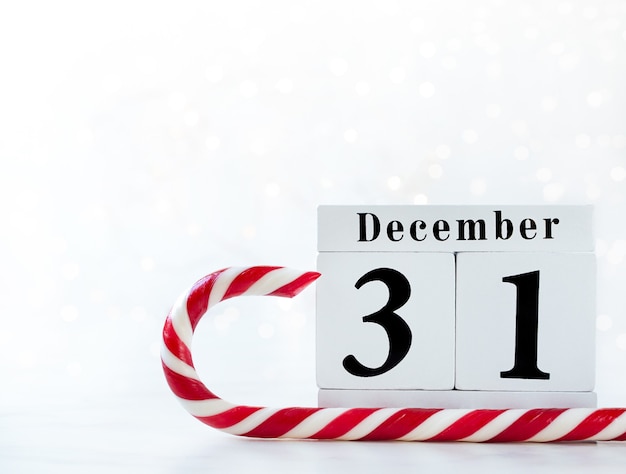 Photo date du nouvel an sur le calendrier. calendrier en bois du 31 décembre avec sucette rouge et blanche