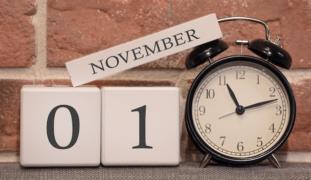 Date importante, le 1er novembre, saison d'automne. Calendrier en bois sur fond de mur de briques. Réveil rétro comme concept de gestion du temps.