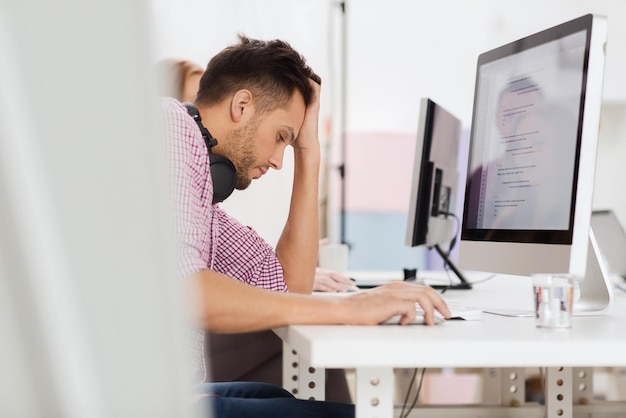 date limite, démarrage, éducation, technologie et concept de personnes - développeur de logiciels stressé triste ou étudiant avec casque et ordinateur au bureau