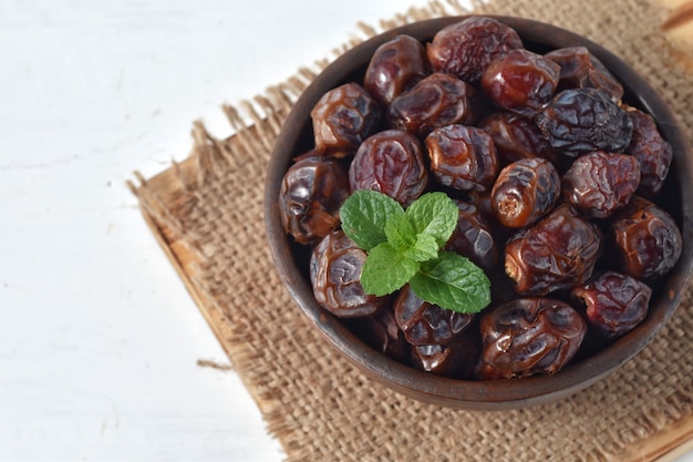 Date séchée et menthe verte dans un bol sur blanc