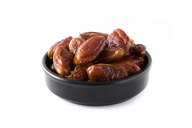 Dates dans un bol noir isolé sur blanc