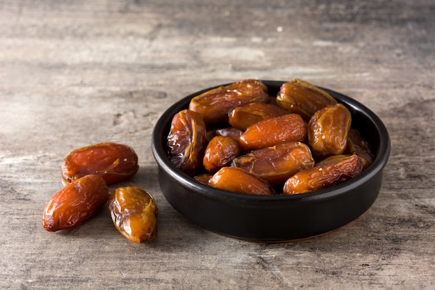 Dates dans un bol noir sur table en bois