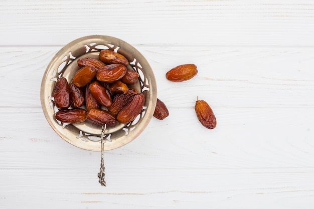 Dates de fruits sur une petite assiette sur une table blanche