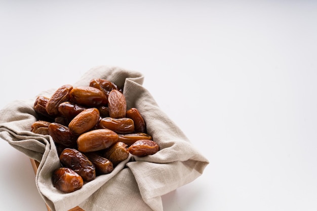 Dattes séchées fruits dans un plateau en bois isolé sur fond blanc