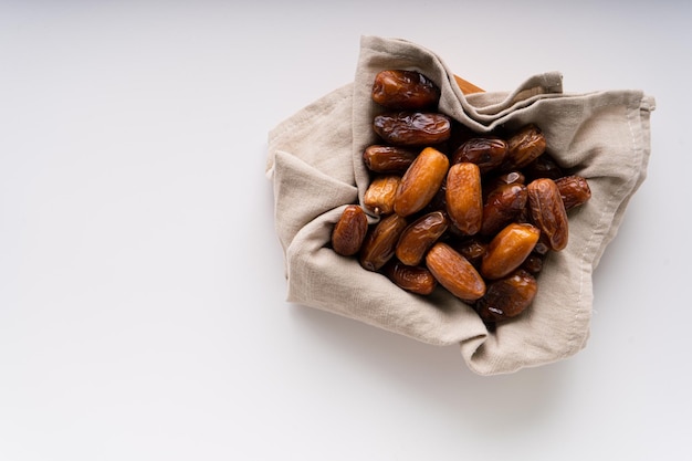 Dattes séchées fruits dans un plateau en bois isolé sur fond blanc