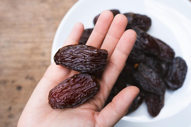 Photo les dattes séchées medjool tenues dans les mains d'une femme sont un fruit riche en nutriments