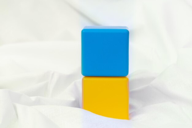 Un dé bleu se dresse sur un dé jaune sur un fond blanc dés pour enfants pour jouer sous la forme d'un drapeau bleu-jaune de l'Ukraine