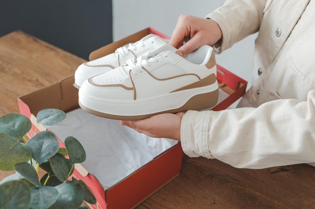 Déballer les chaussures pour femmes élégantes baskets blanches dans les mains