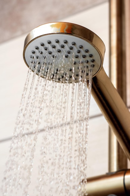 Le débit d'eau de l'arrosoir dans la douche en gros plan Prendre une douche