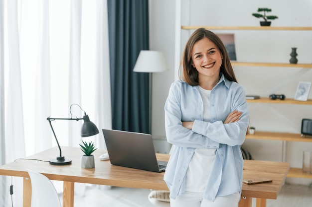 Debout, les bras croisés Jeune belle femme est seule à la maison dans la chambre domestique