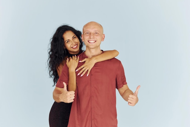 Debout dans le studio sur fond blanc Un couple joyeux est ensemble à l'intérieur