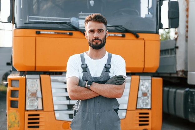 Debout et posant pour la caméra Homme en uniforme faisant du service pour un gros camion