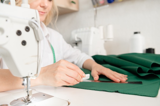 debout près de la table à la maison tenant une règle couture matériel textile femme passe-temps vue latérale