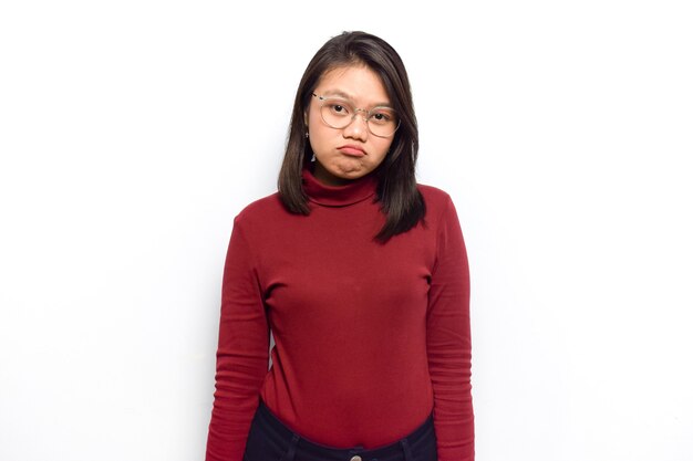 Debout avec un visage sérieux et regardant la caméra de jeunes belles femmes asiatiques s'habillent d'une chemise rouge