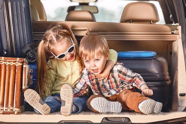 Début du voyage petits enfants mignons dans le coffre d'une voiture avec des valises