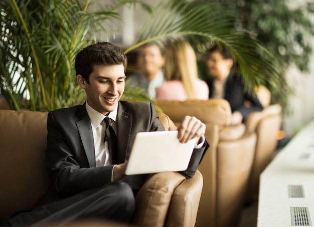 Débutant entrepreneur avec une tablette numérique assis sur le canapé