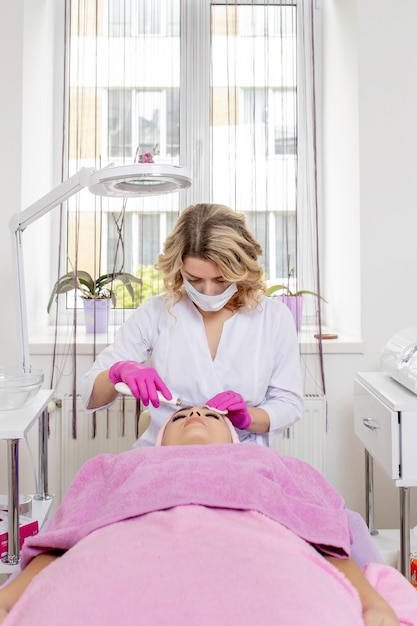 Décapage par ultrasons. Jeune femme recevant un peeling facial par cavitation par ultrasons. Nettoyage de traitement de soins de la peau du visage de cosmétologie. Mains d'esthéticienne au travail, nettoyant la peau au jet d'eau.