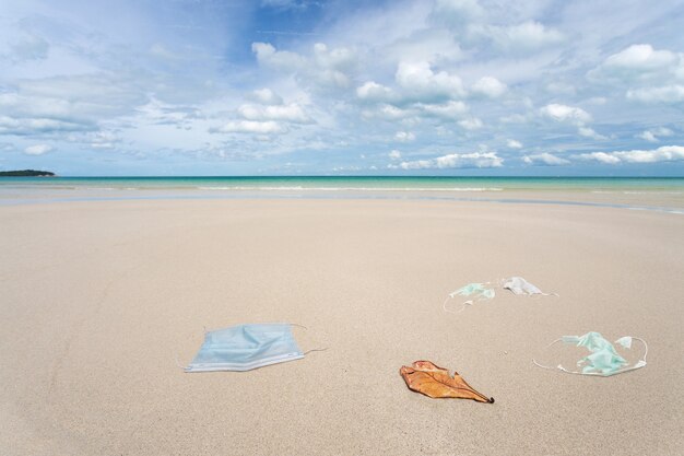 Déchets de masques médicaux usagés sur la plage.