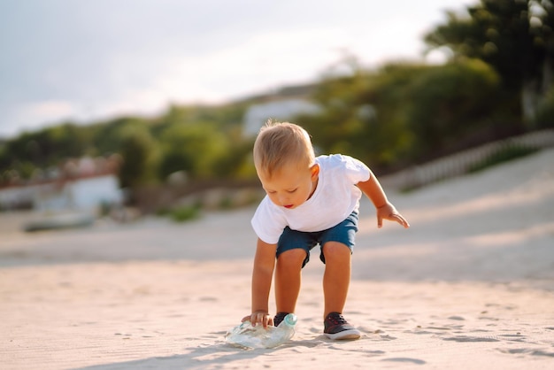 Déchets sur la plage Scavengery Child ramasse des déchets plastiques sur la plage au bord de la mer