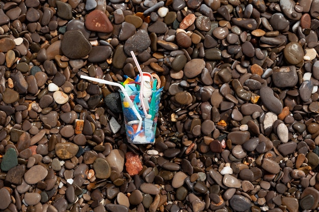 Déchets plastiques sur galets mouillés au bord de la mer Utilisation excessive d'emballages plastiques jetables