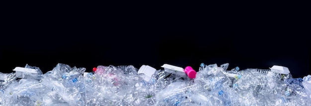 Déchets poubelles et emballages plastiques usagés non dégradables sur fond noir