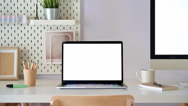 Décor de bureau avec maquette d&#39;ordinateur portable à écran blanc. Espace de travail minimal