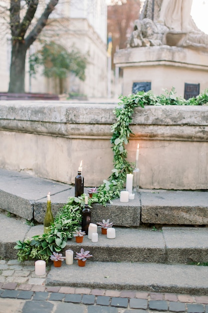 Décor de cérémonie de mariage, escaliers en pierre décorés avec des bougies allumées blanches et de la verdure fraîche, des fleurs et des succulentes