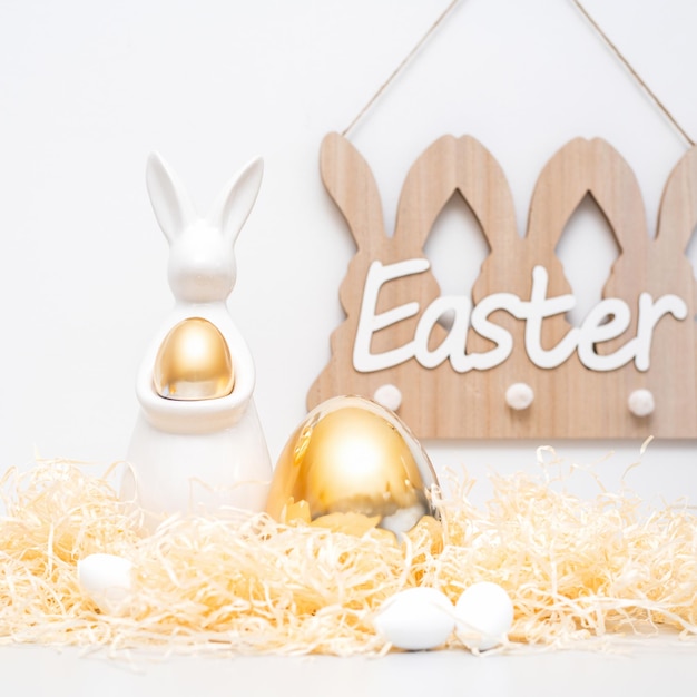 Le décor du lapin d'ester doré est un concept de vacances de chaume et d'œufs.