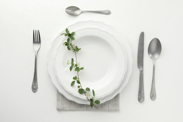 Un décor élégant avec des couverts et des assiettes sur une table à texture blanche.