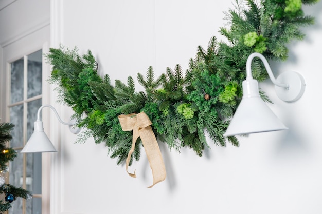 Un décor fait de branches d'arbres de Noël est accroché au mur près d'une applique blanche Décor festif du Nouvel An sur le mur à la maison