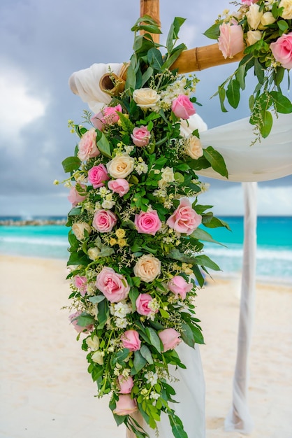 Décor de fleurs de roses blanches et roses sur une arche de mariage