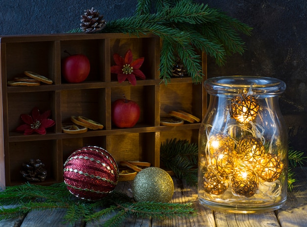 décor d&#39;hiver sur une table en bois: pommes, branches de sapin, cônes, boules et guirlande