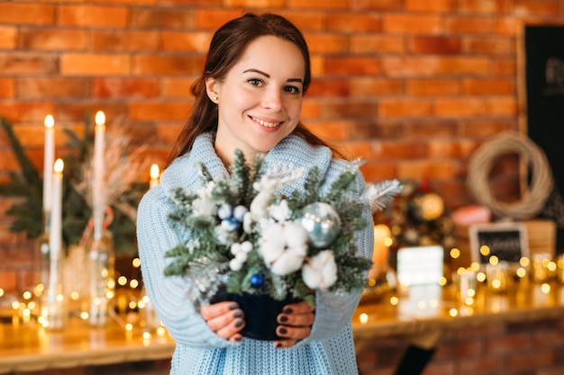 Décor intérieur festif. Portrait de femme joyeuse tenant arrangement de sapin