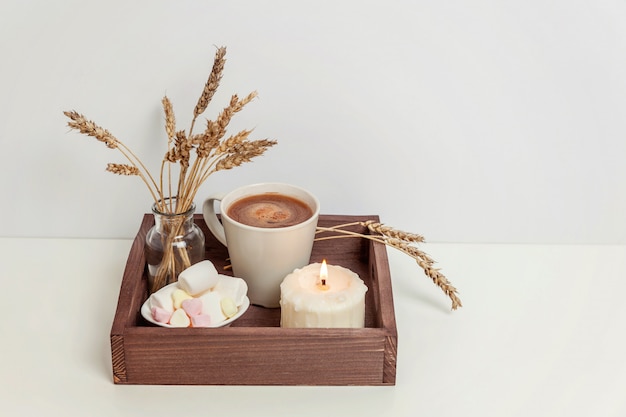 Décor à la maison écologique naturel avec tasse de guimauve au café et bougie sur un plateau en bois