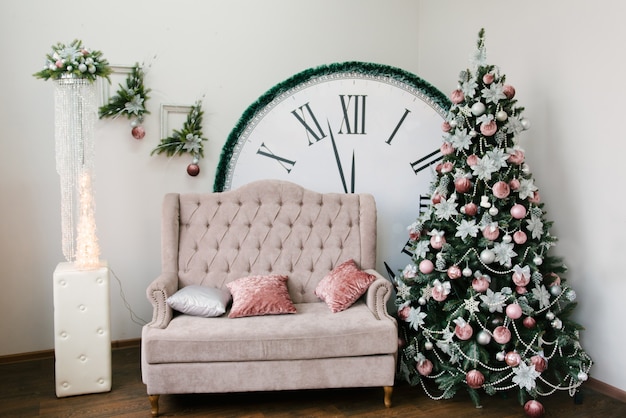 Le décor de Noël et du nouvel an. Sapin de Noël, canapé et une grande horloge qui affiche 12 heures